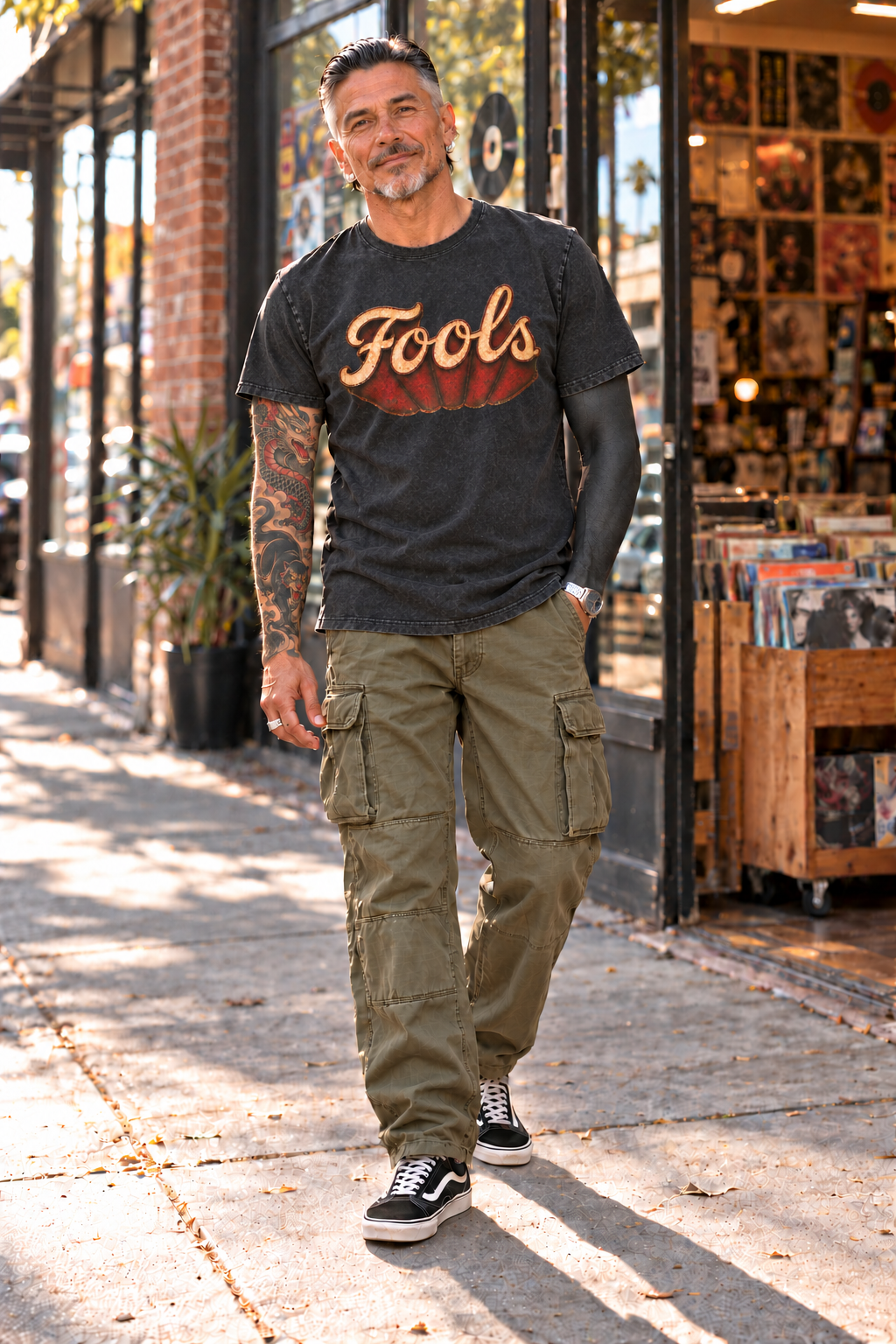 FOOLS Dive Bar Tee styled with olive military cargo pants and black skate shoes outside a record shop.