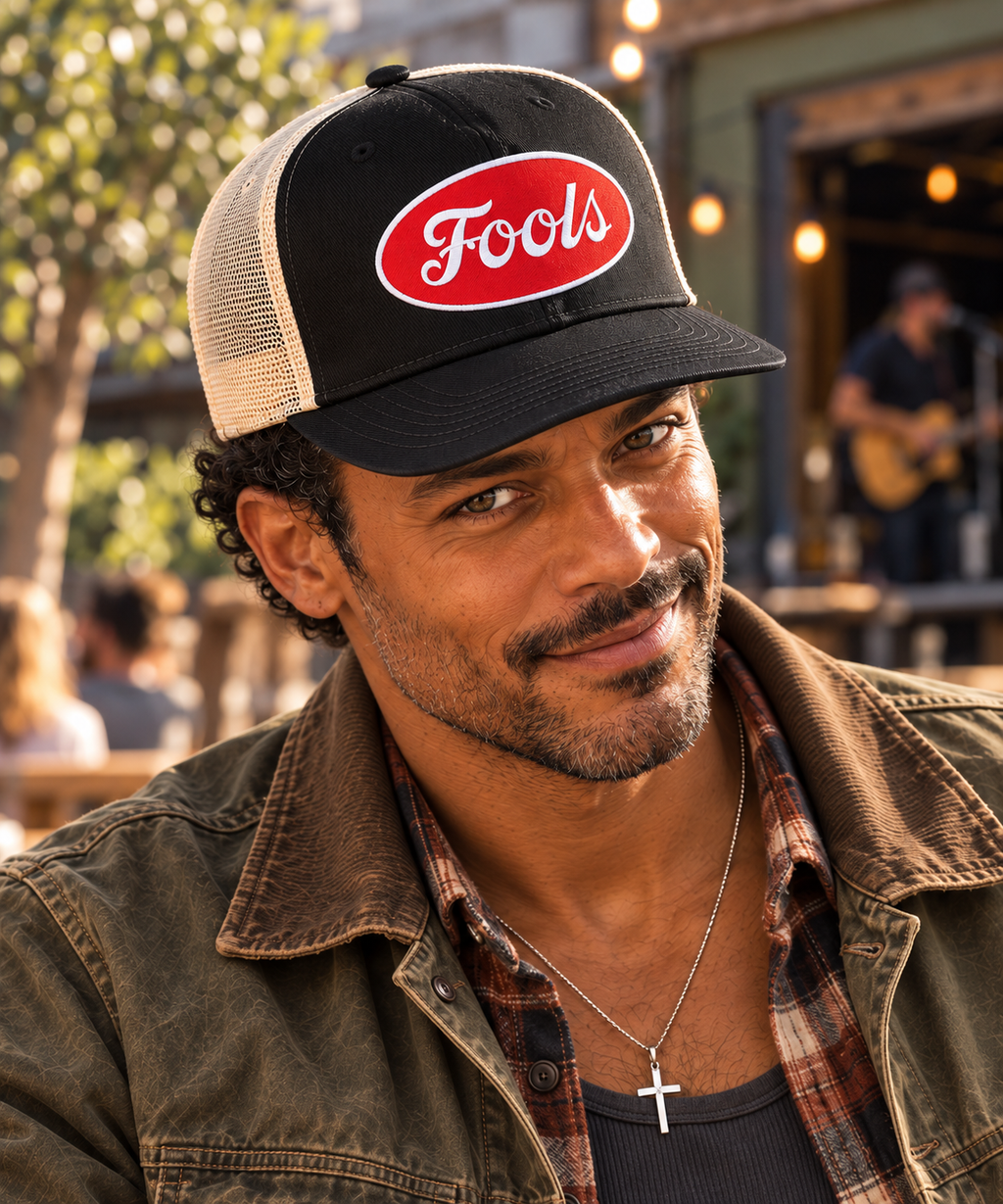 Close-up of the FOOLS Good Times Snap Back with black twill front, ecru mesh and red oval FOOLS patch, worn with vintage workwear.