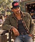 Man wearing the black and ecru FOOLS Good Times Snap Back with an olive canvas work jacket, vintage plaid flannel and silver cross necklace.