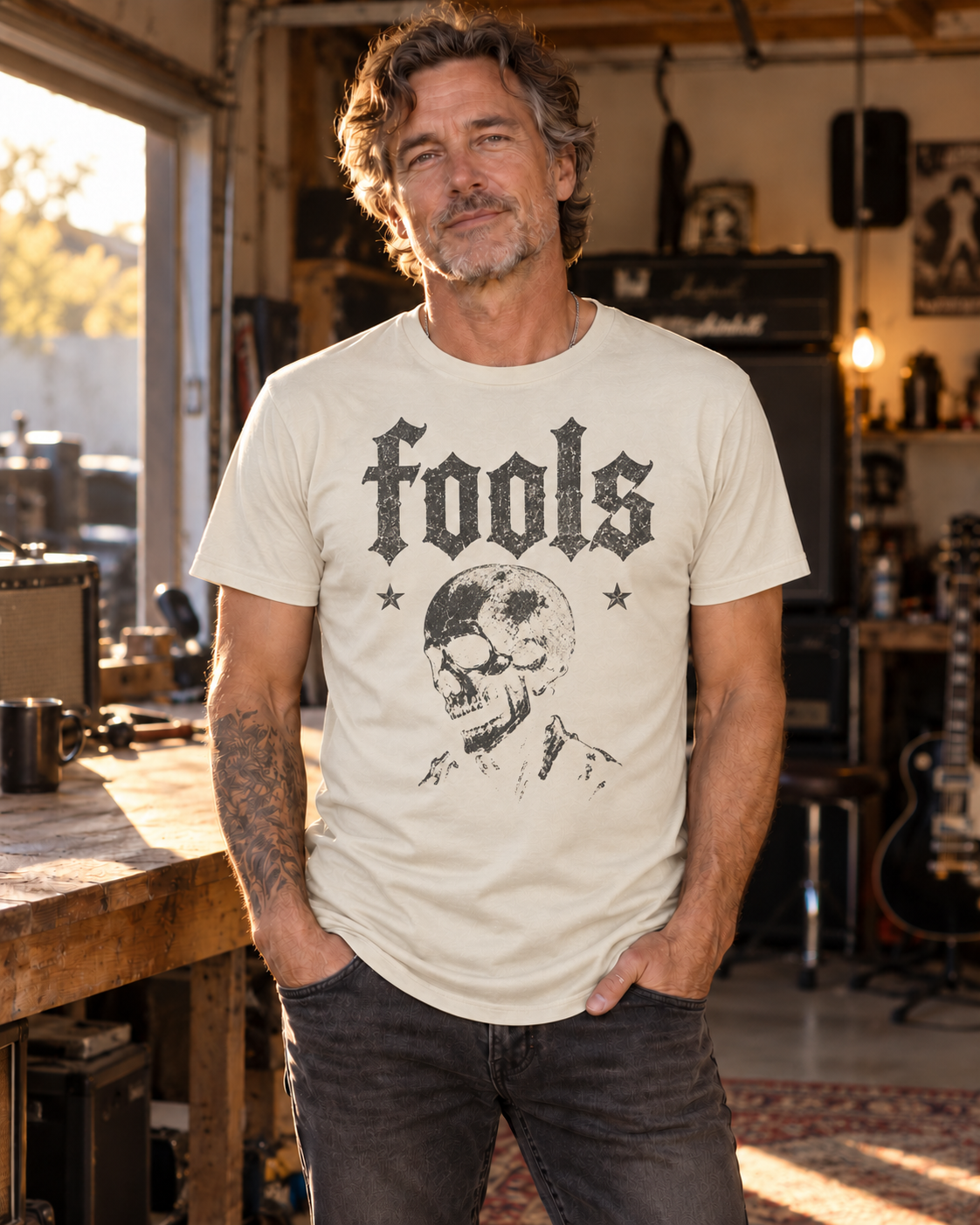 Model concept showing the FOOLS men's Ecru curved-hem tee with distressed faded-charcoal vintage skull artwork.