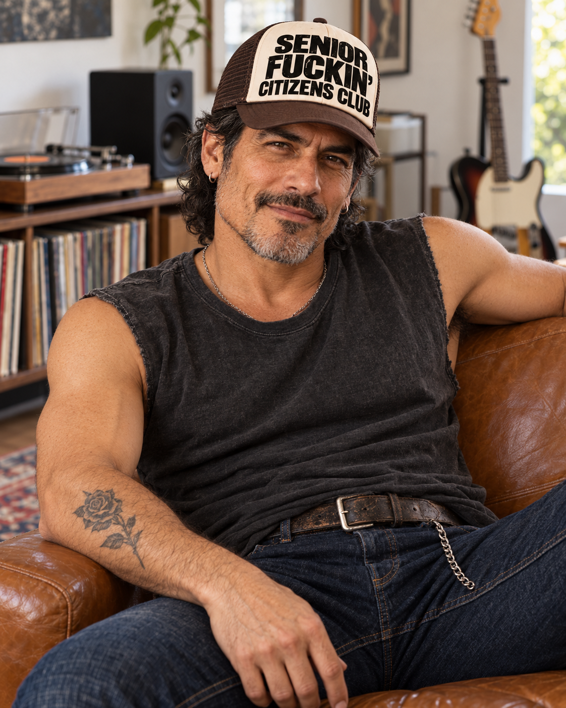 FOOLS beige and brown Senior Fuckin’ Citizens Club trucker hat on a man in a washed charcoal sleeveless tee, seated in a vinyl listening room