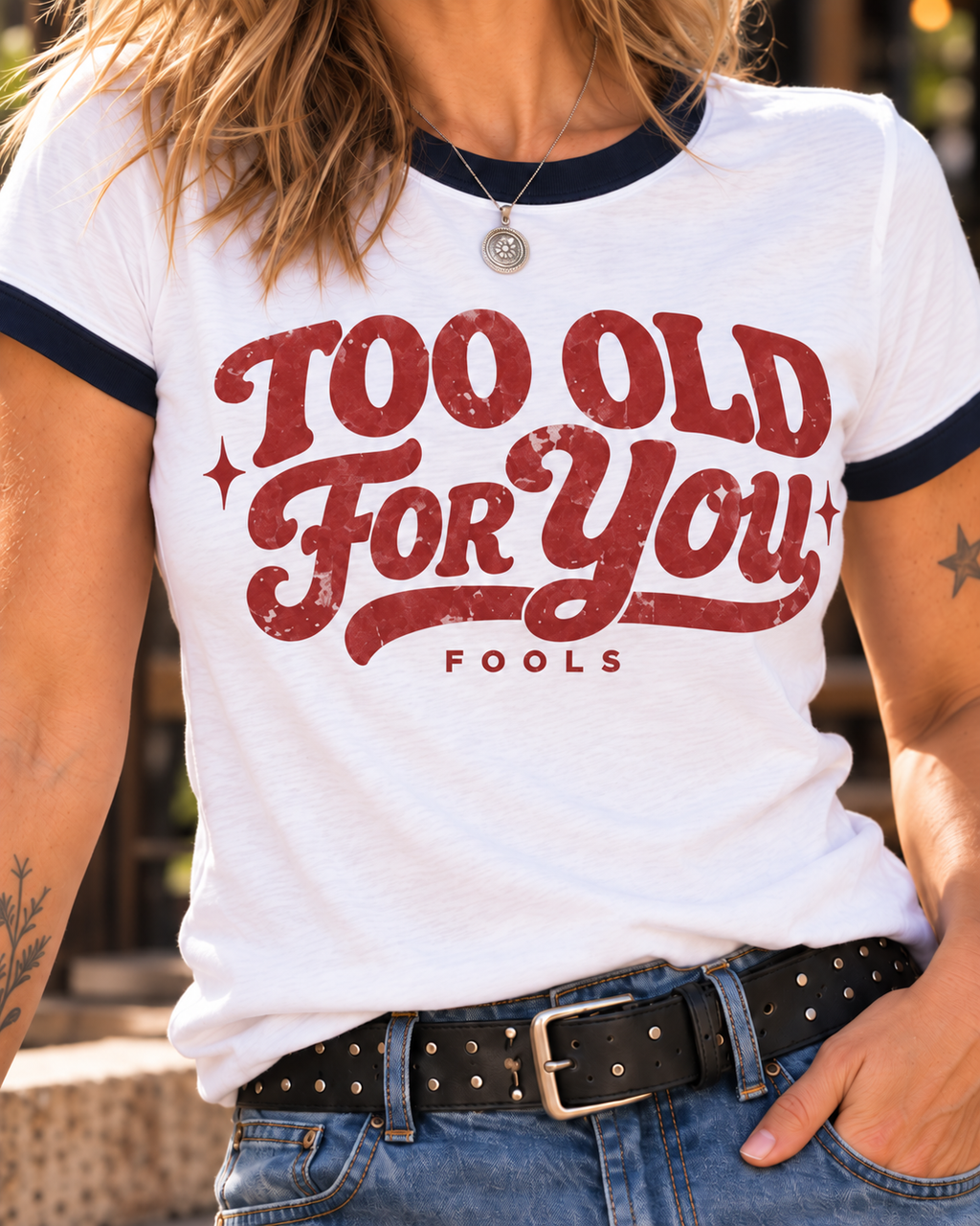 Close-up of faded cherry-red Too Old for You FOOLS print on white tee with navy trim